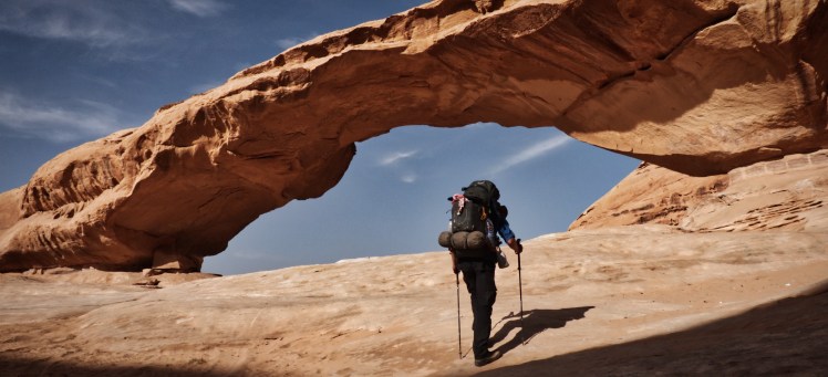 Author walking towards the great rock arch at Jebel Kharazeh, Jordan